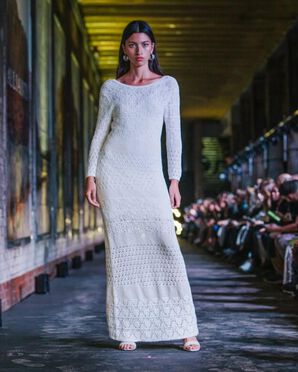 A woman wearing a white maxi crochet dress catwalking.