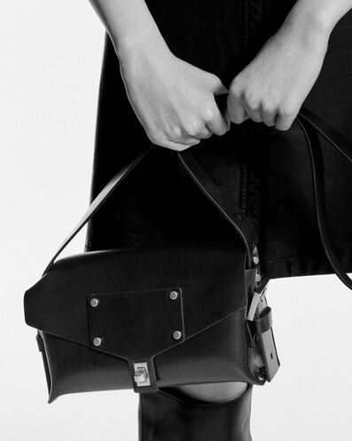 A black and white picture of a woman holding a black leather bag.