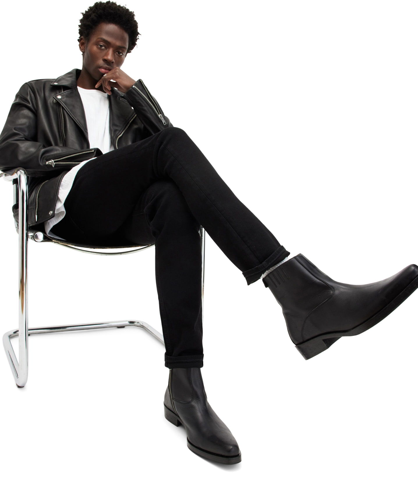 Closeup of man sitting in metal chair wearing leather boots.