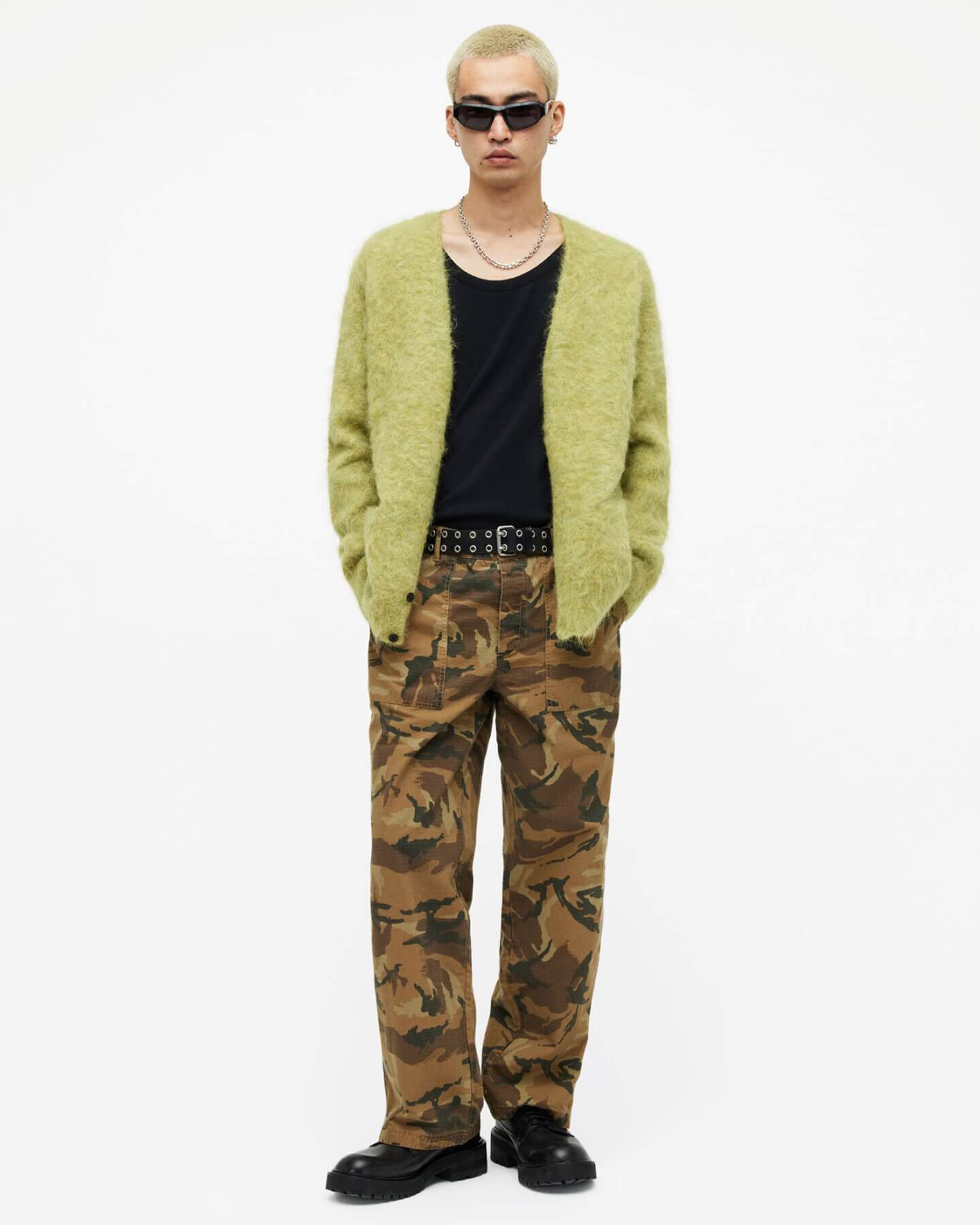 Man wearing a yellow cardigan and camo trousers.