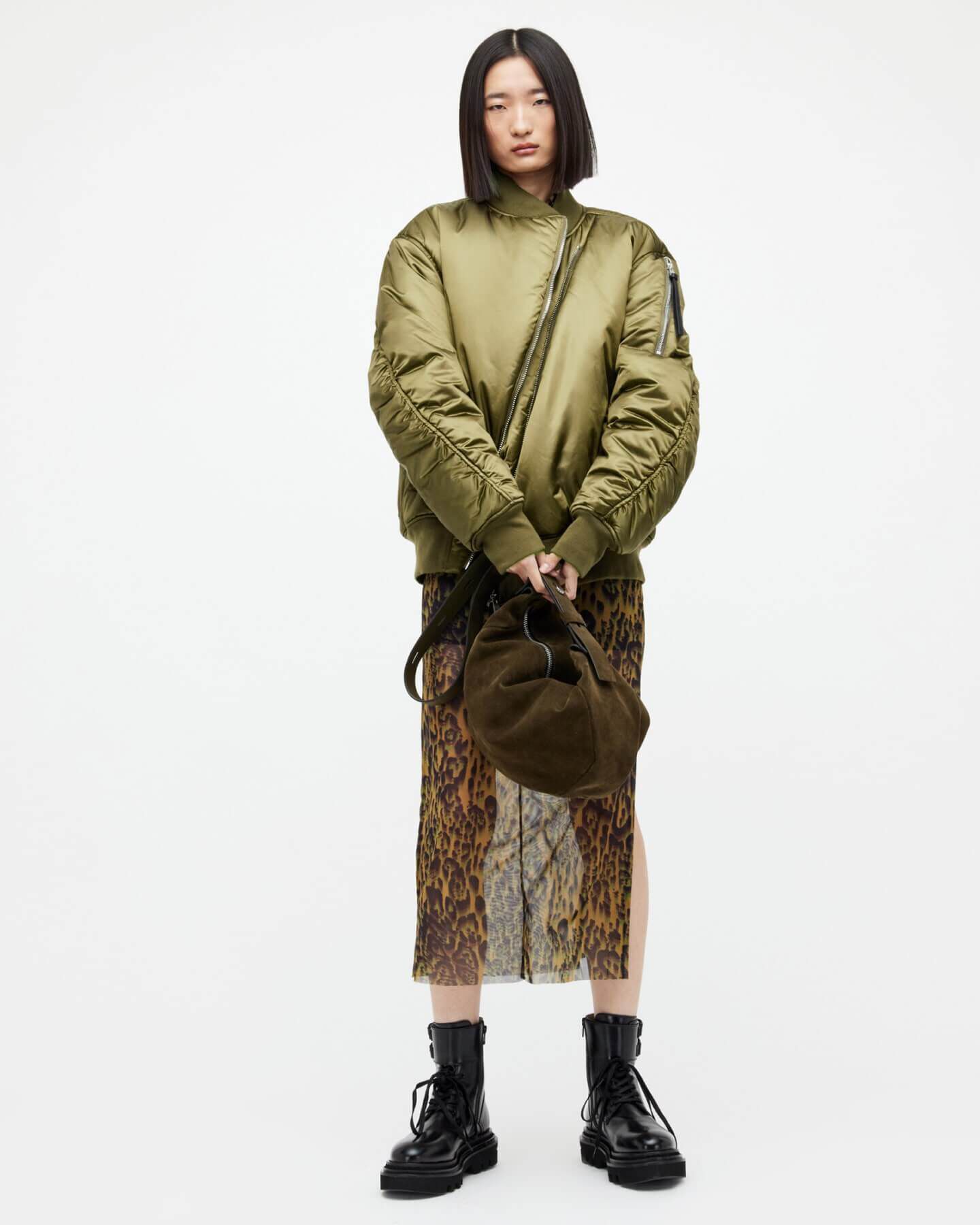 A woman wearing a khaki bomber and transparent skirt.