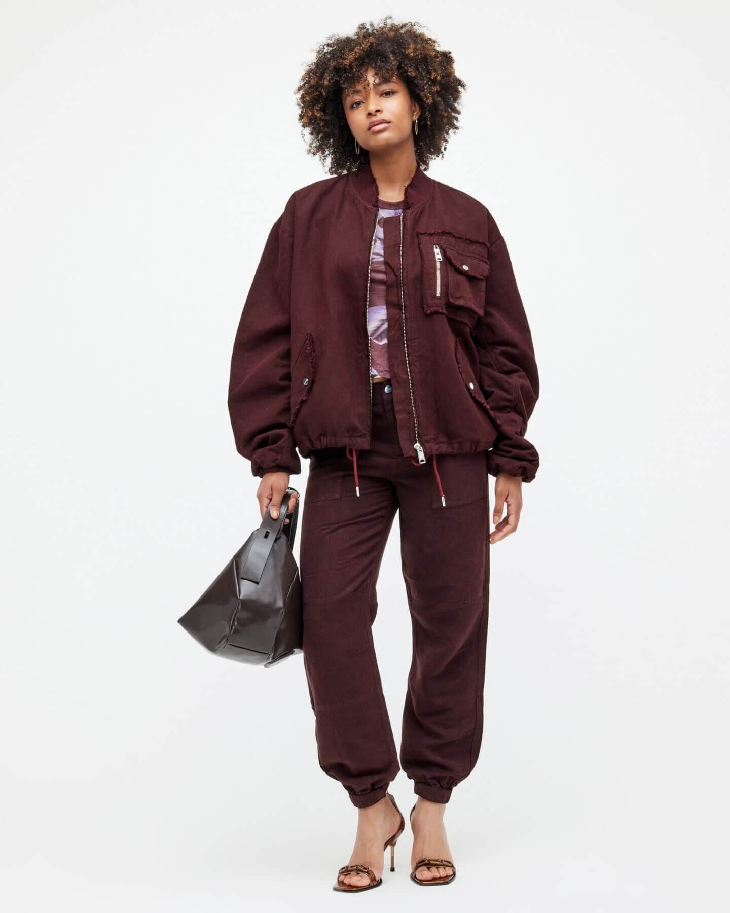 Woman wearing a burgundy bomber jacket & burgundy trousers.