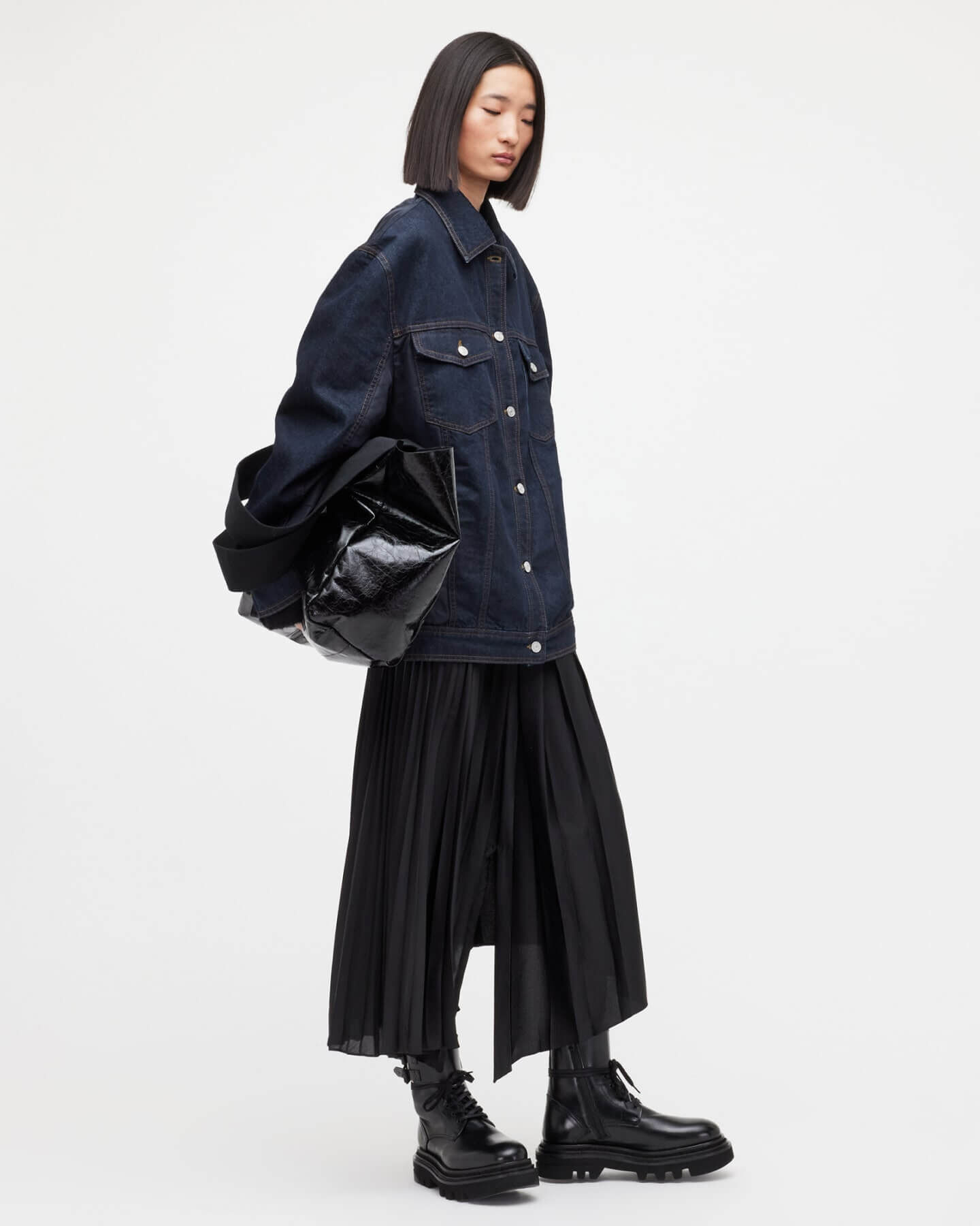 Woman wearing a oversized denim jacket and plissé skirt.