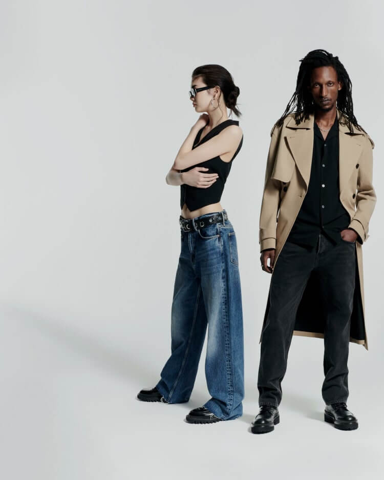 Man and woman stood in black clothing, leather jackets and sunglassed in the desert.