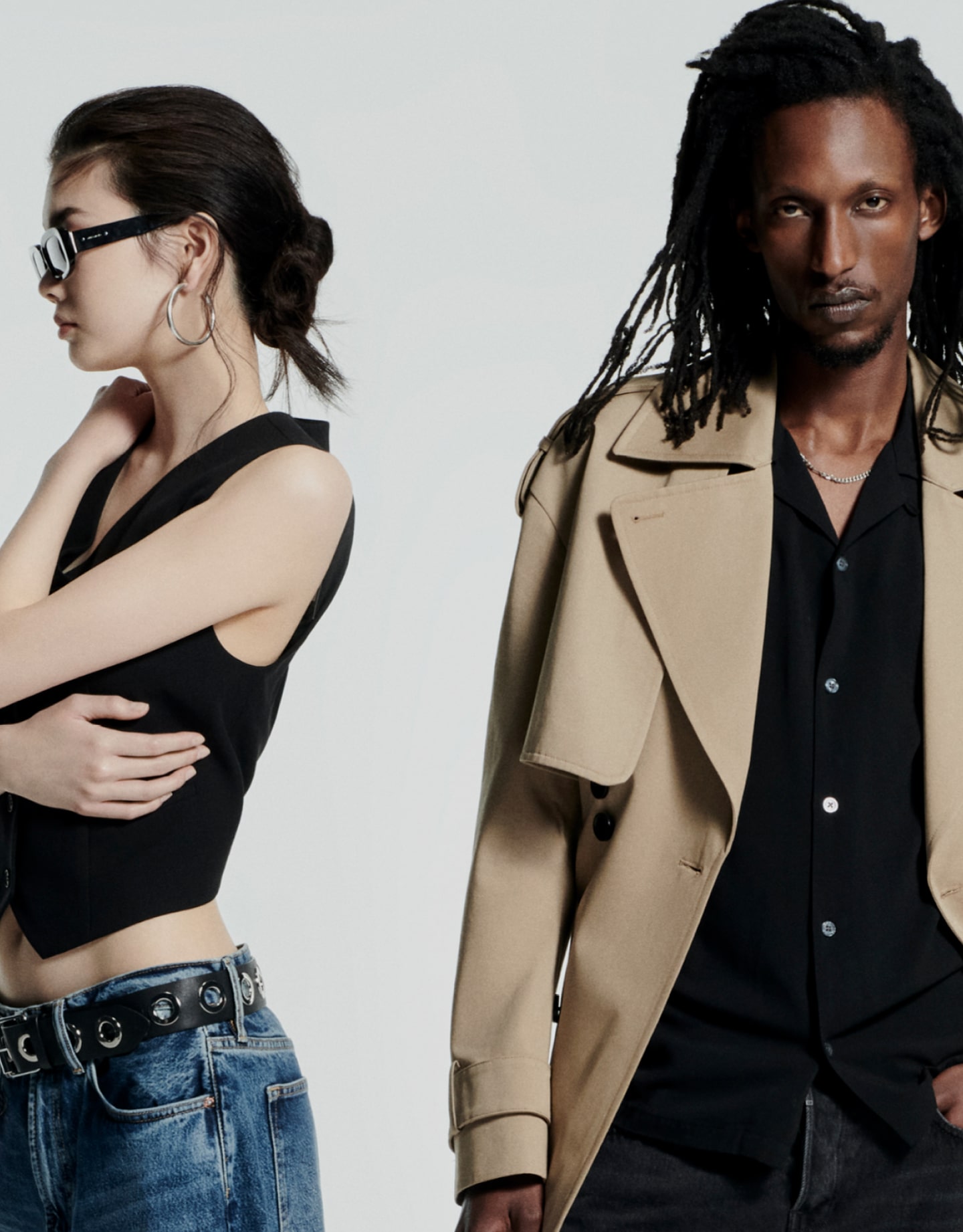 A female and a male model wearing AllSaints clothes standing in front of a pale grey background.